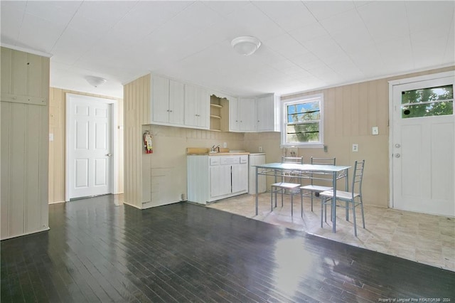 kitchen featuring white cabinetry, wood walls, sink, and dark hardwood / wood-style floors