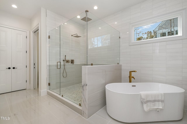 bathroom with tile walls and separate shower and tub