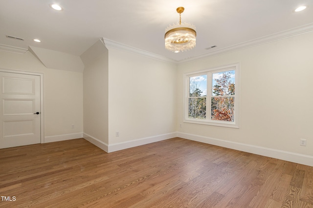 empty room with crown molding, wood-type flooring, and an inviting chandelier