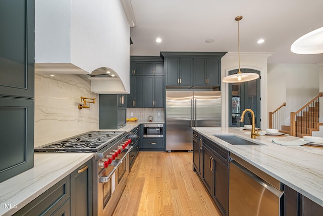 kitchen featuring pendant lighting, backsplash, sink, and high end appliances