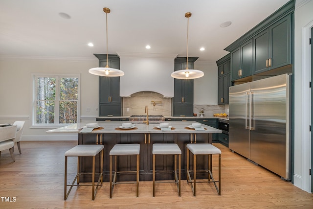 kitchen with a center island with sink, decorative light fixtures, and high quality fridge