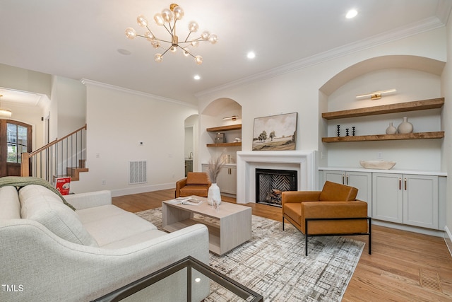 living room with crown molding, light wood-type flooring, and built in shelves