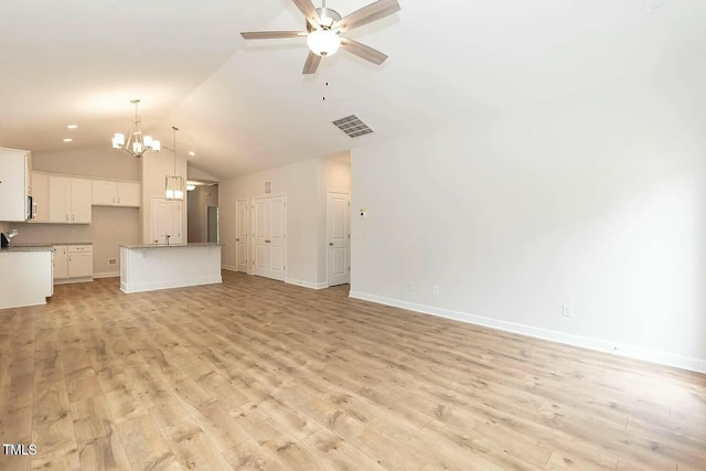 unfurnished living room with ceiling fan with notable chandelier, light hardwood / wood-style floors, and vaulted ceiling