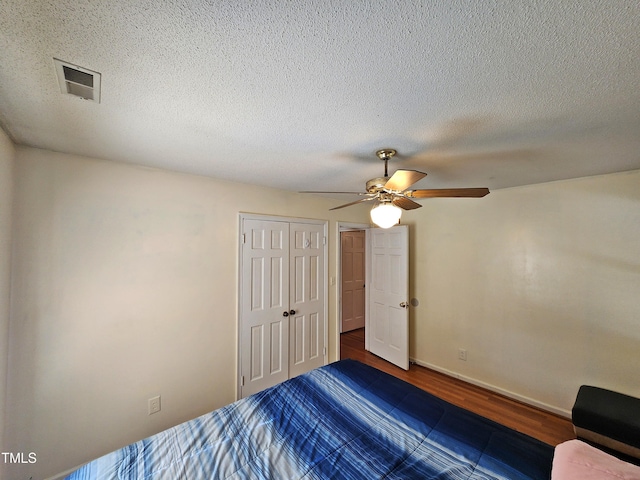 bedroom featuring hardwood / wood-style floors, a textured ceiling, ceiling fan, and a closet