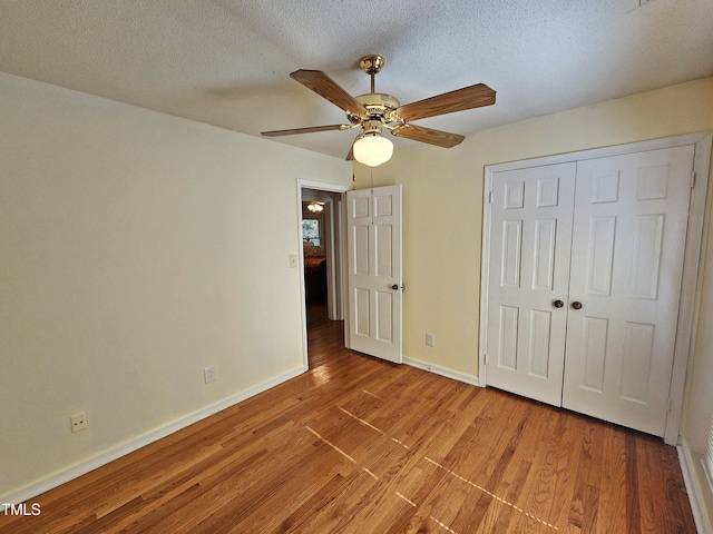 unfurnished bedroom with a closet, light hardwood / wood-style floors, a textured ceiling, and ceiling fan