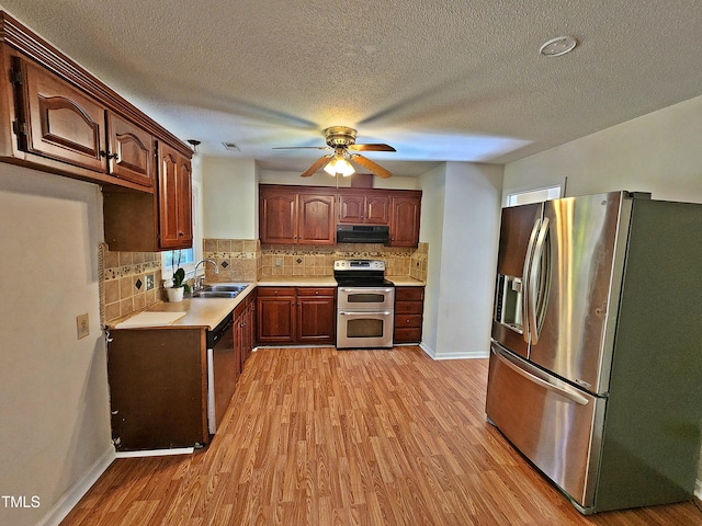 kitchen featuring extractor fan, appliances with stainless steel finishes, light wood-type flooring, sink, and ceiling fan