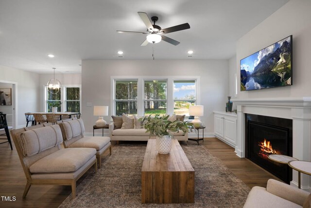 living room with ceiling fan with notable chandelier and dark wood-type flooring