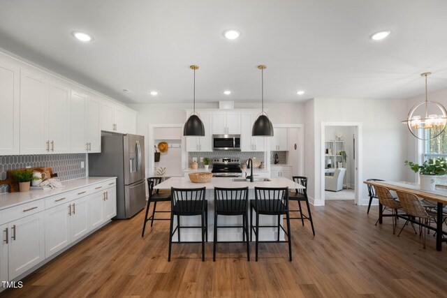 kitchen with stainless steel appliances, hanging light fixtures, and white cabinets