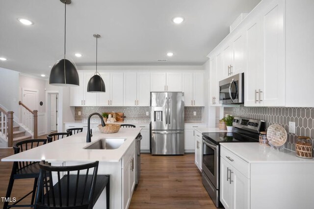 kitchen with appliances with stainless steel finishes, sink, hanging light fixtures, and white cabinetry