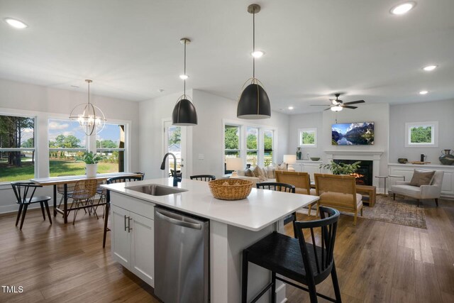 kitchen with sink, decorative light fixtures, stainless steel dishwasher, white cabinets, and a kitchen island with sink