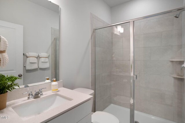 bathroom with vanity, a shower with door, and toilet