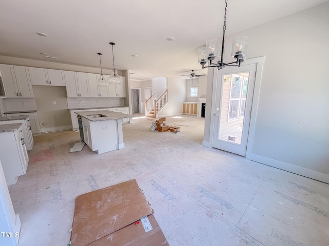 kitchen with sink, a center island, white cabinets, hanging light fixtures, and decorative backsplash