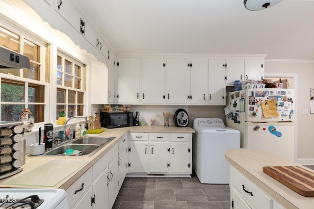 kitchen featuring white fridge, washer / dryer, white cabinetry, and sink