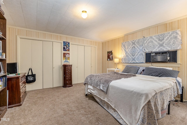 bedroom with cooling unit, crown molding, carpet, and two closets