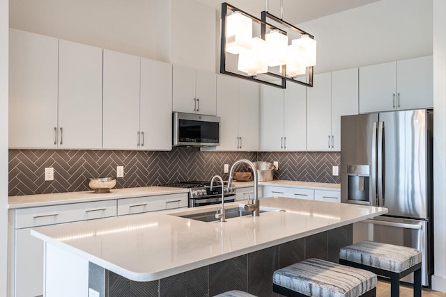 kitchen featuring sink, stainless steel appliances, pendant lighting, a breakfast bar, and white cabinets