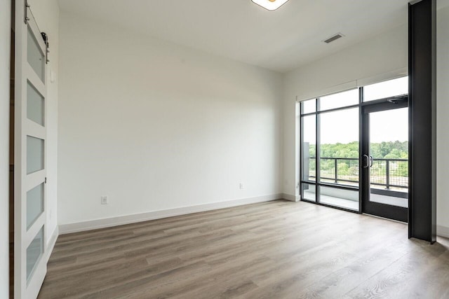 empty room with hardwood / wood-style flooring and a barn door