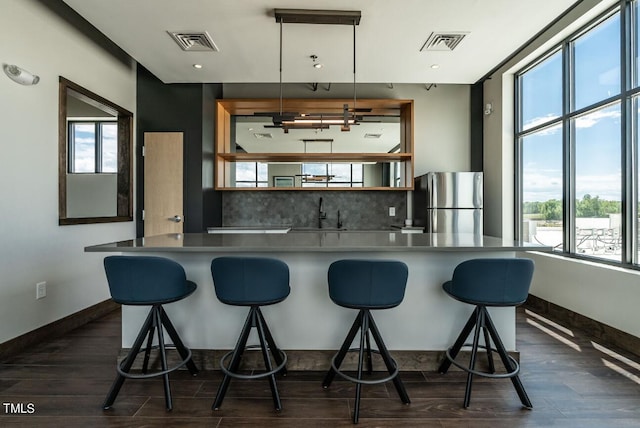 kitchen featuring decorative light fixtures, stainless steel fridge, dark hardwood / wood-style flooring, and a healthy amount of sunlight