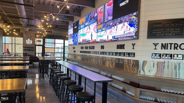 bar featuring beamed ceiling, concrete floors, and an inviting chandelier