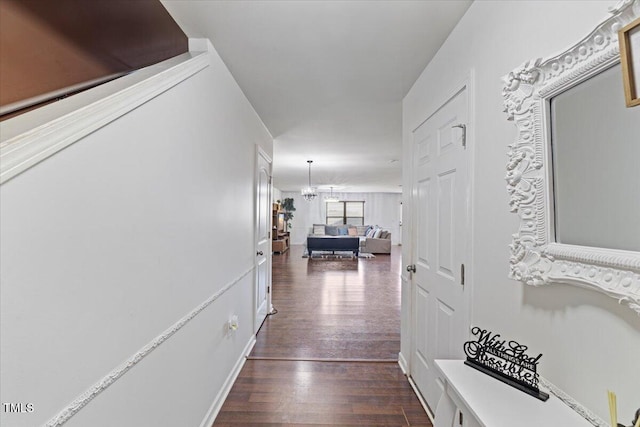 hallway with dark hardwood / wood-style flooring and a chandelier