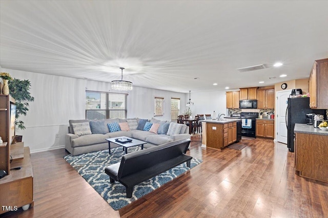 living room featuring sink, a notable chandelier, and wood-type flooring