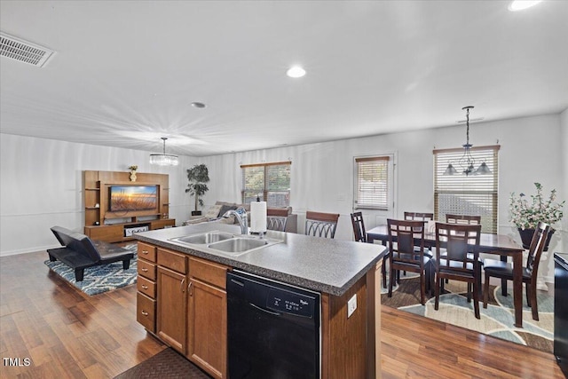 kitchen featuring dark hardwood / wood-style floors, black dishwasher, a center island with sink, sink, and decorative light fixtures