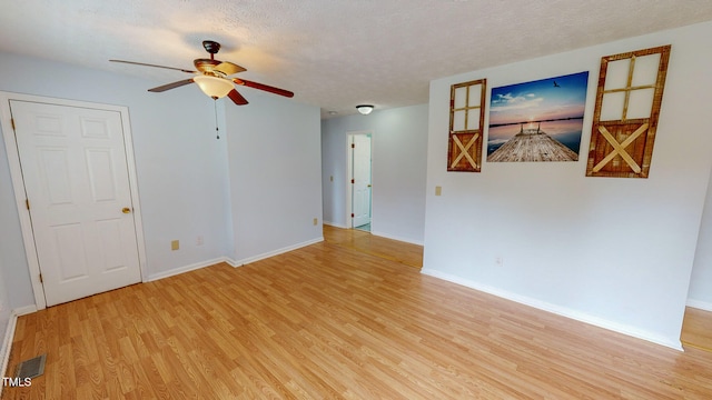 unfurnished room with ceiling fan, a textured ceiling, and light wood-type flooring