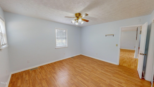 empty room with light hardwood / wood-style floors, ceiling fan, and a textured ceiling