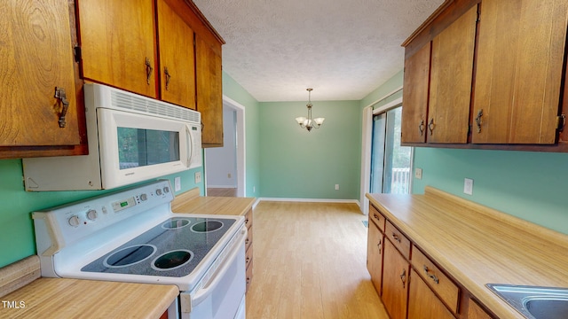 kitchen featuring light hardwood / wood-style floors, an inviting chandelier, a textured ceiling, pendant lighting, and white appliances