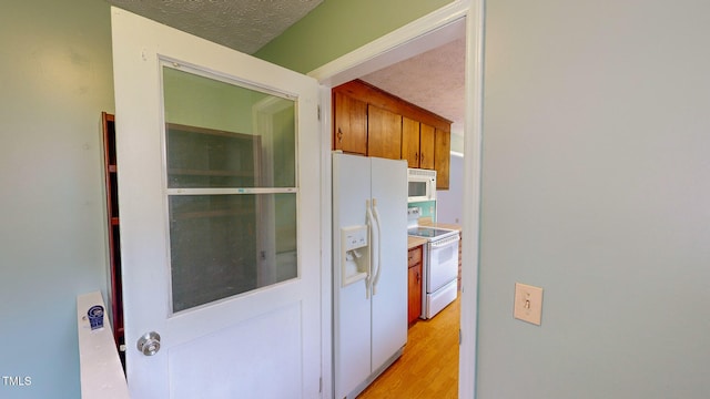 interior space featuring white appliances, a textured ceiling, and light wood-type flooring