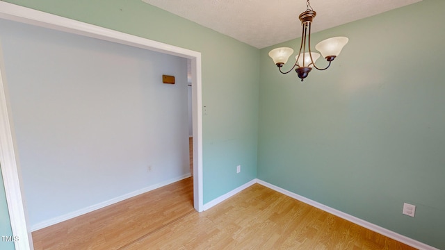 spare room with a chandelier, a textured ceiling, and hardwood / wood-style flooring