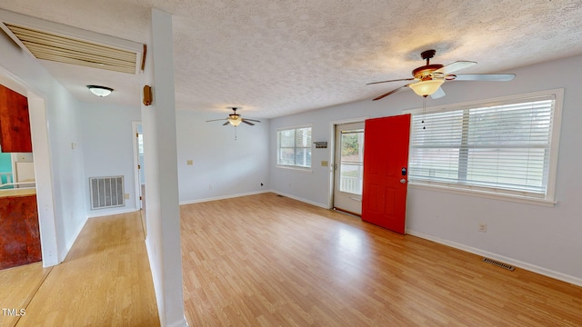 unfurnished living room with light hardwood / wood-style floors and a textured ceiling