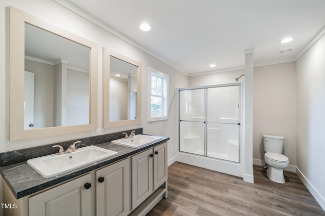 bathroom featuring ornamental molding, vanity, hardwood / wood-style flooring, toilet, and a shower with shower door