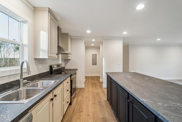 kitchen featuring sink, appliances with stainless steel finishes, ornamental molding, wall chimney exhaust hood, and light wood-type flooring