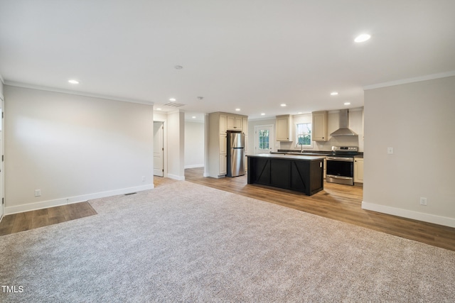 kitchen featuring crown molding, a kitchen island, wall chimney range hood, appliances with stainless steel finishes, and light hardwood / wood-style floors