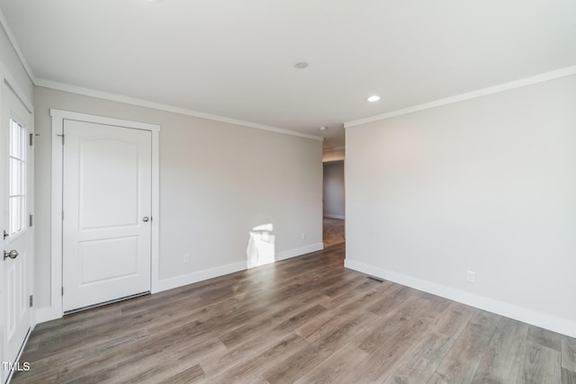 spare room featuring wood-type flooring and crown molding