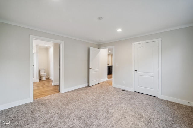 unfurnished bedroom featuring ensuite bathroom, light colored carpet, and crown molding