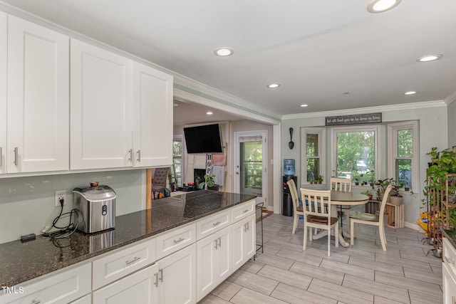 kitchen with dark stone countertops, ornamental molding, and white cabinets