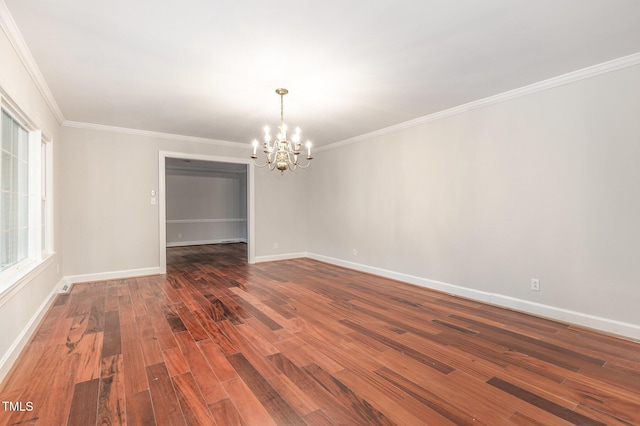 spare room with dark wood-type flooring, crown molding, and a chandelier