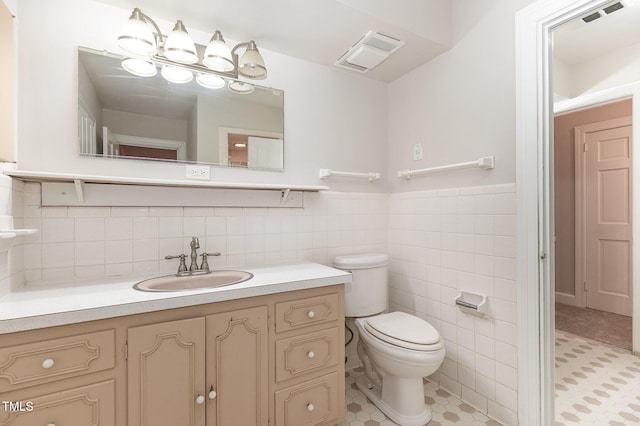 bathroom with tile walls, vanity, tile patterned flooring, and toilet