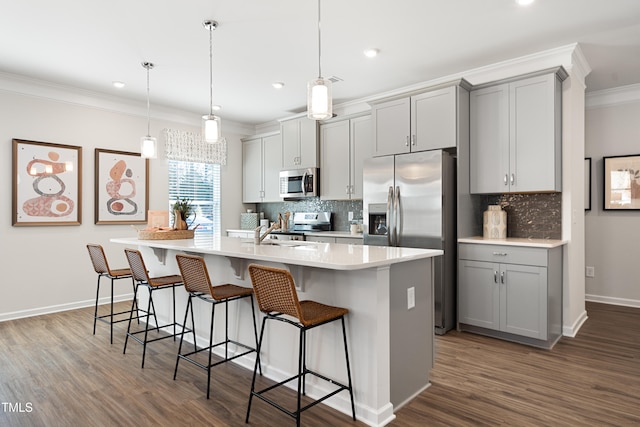 kitchen featuring stainless steel appliances, an island with sink, gray cabinets, and decorative light fixtures