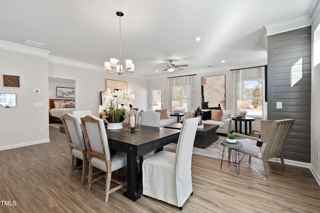 dining room with wood-type flooring, ornamental molding, and ceiling fan with notable chandelier