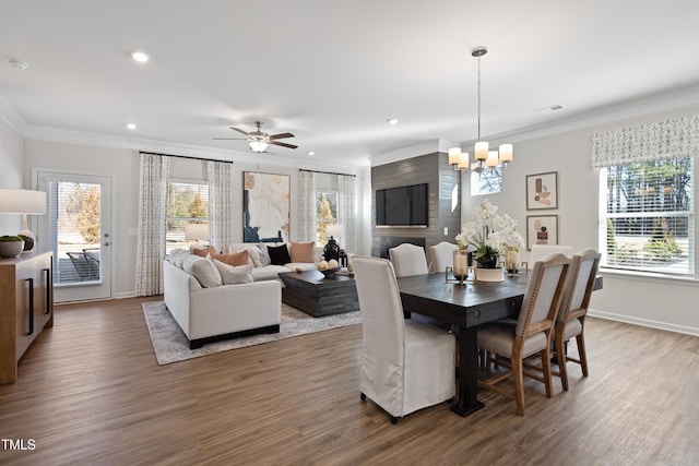 dining room with ornamental molding, ceiling fan with notable chandelier, and wood-type flooring