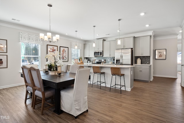 dining area featuring dark wood-type flooring, ornamental molding, and a chandelier