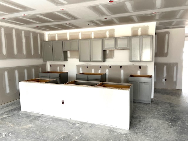 kitchen with concrete flooring, a center island, and gray cabinetry