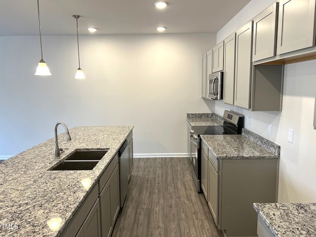 kitchen featuring stainless steel appliances, a sink, dark wood finished floors, and light stone countertops