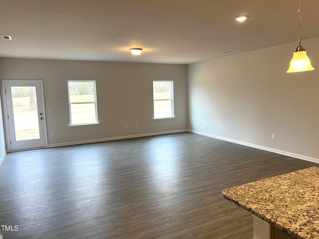 unfurnished living room featuring visible vents, dark wood finished floors, and baseboards