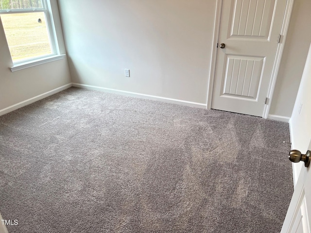 spare room featuring carpet flooring and baseboards