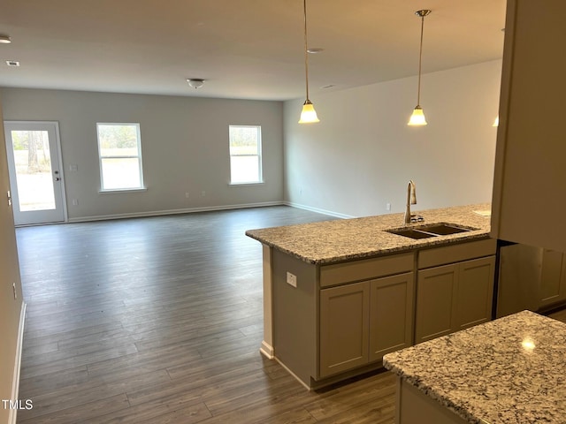 kitchen featuring light stone countertops, dark wood-style floors, a sink, and decorative light fixtures