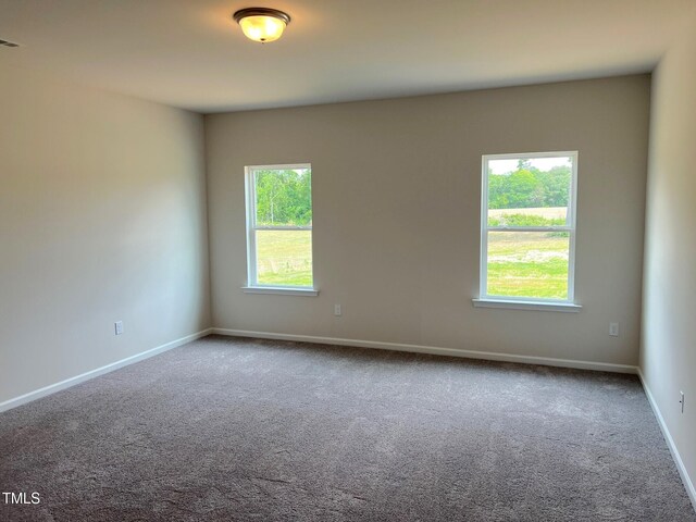 spare room featuring carpet and baseboards