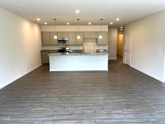 kitchen with recessed lighting, appliances with stainless steel finishes, a sink, gray cabinetry, and a center island with sink